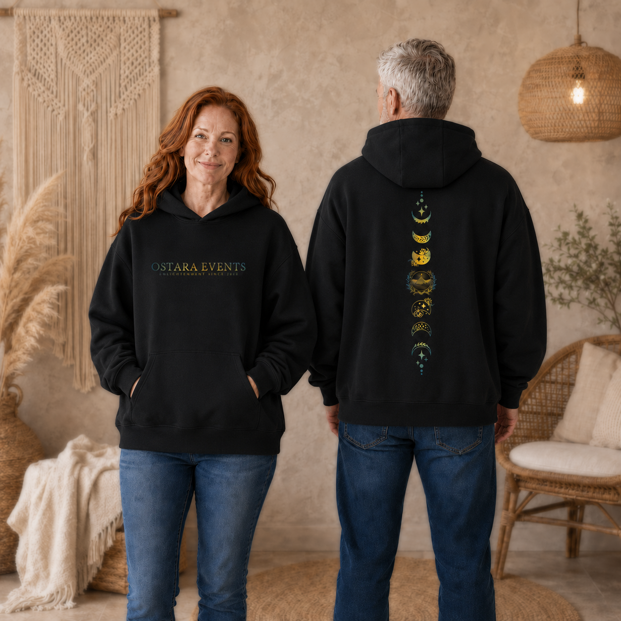 Two people wearing black hoodies with visible branding in a cozy indoor setting.
